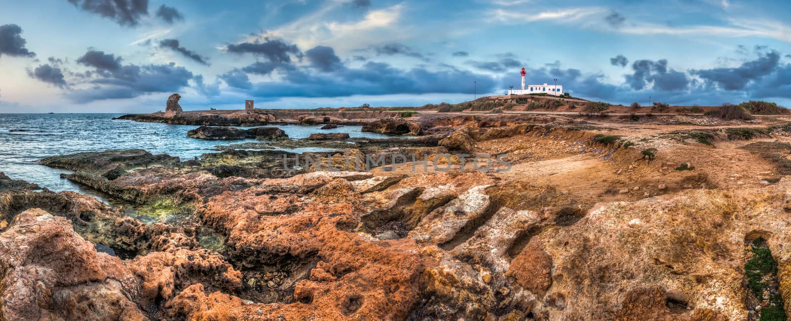 rocky coast with ancient ruins and lighthouse in the morning