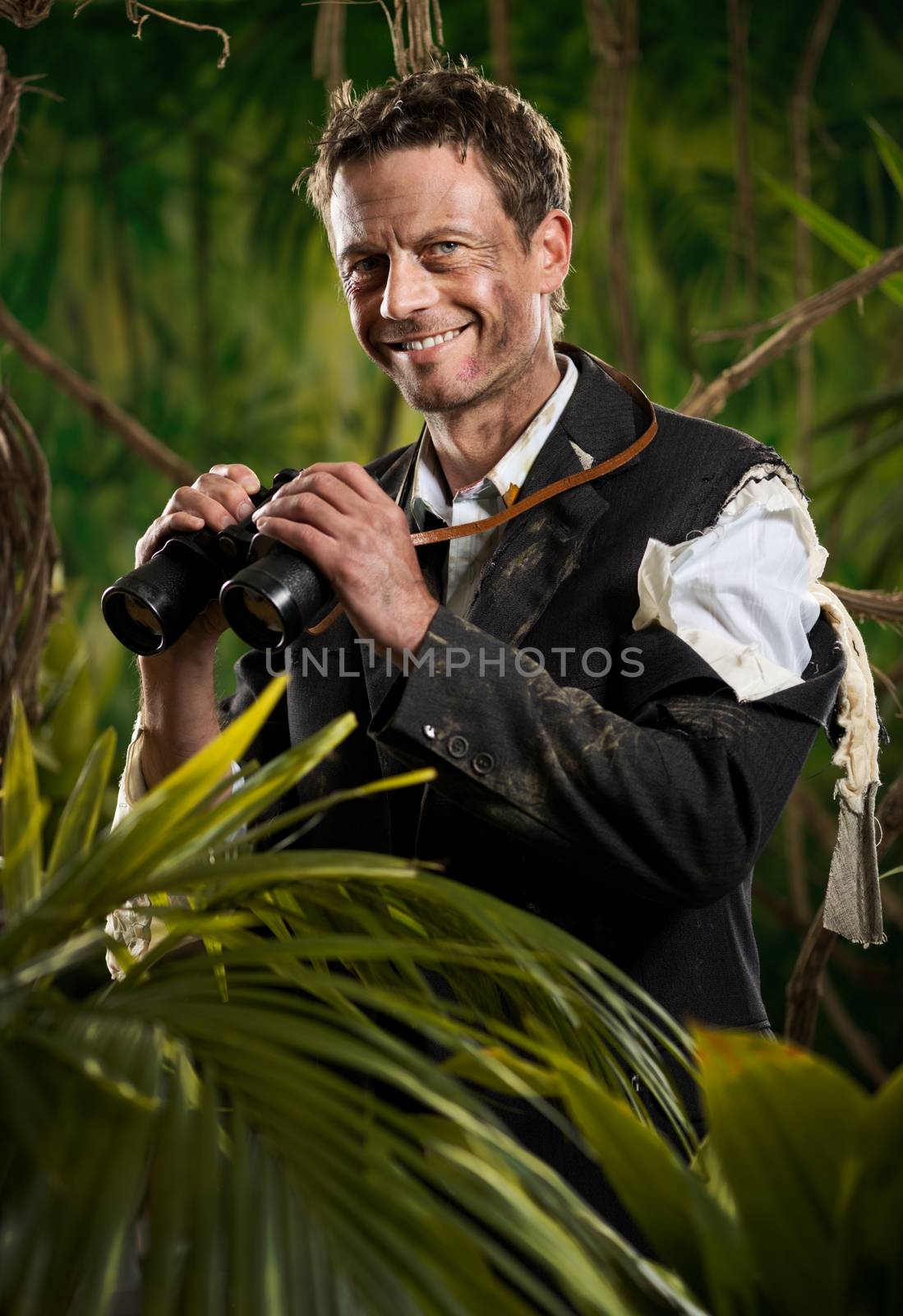 Confident businessman holding binoculars and exploring jungle.