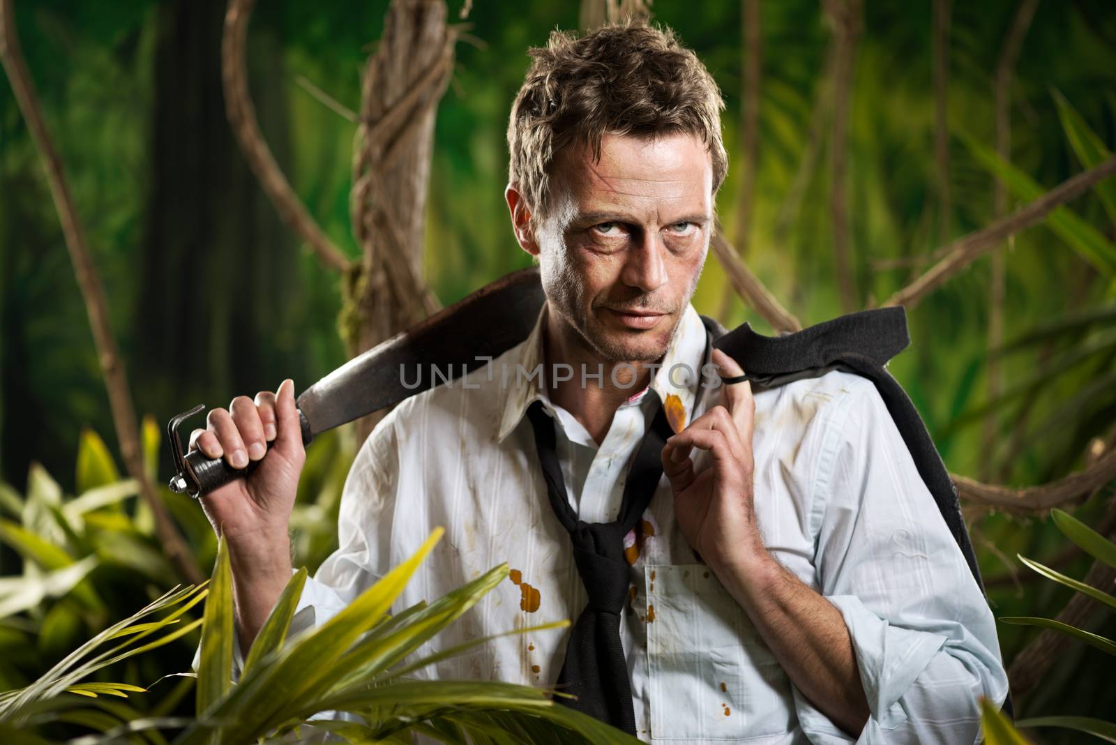 Attractive confident businessman with machete walking in the jungle.