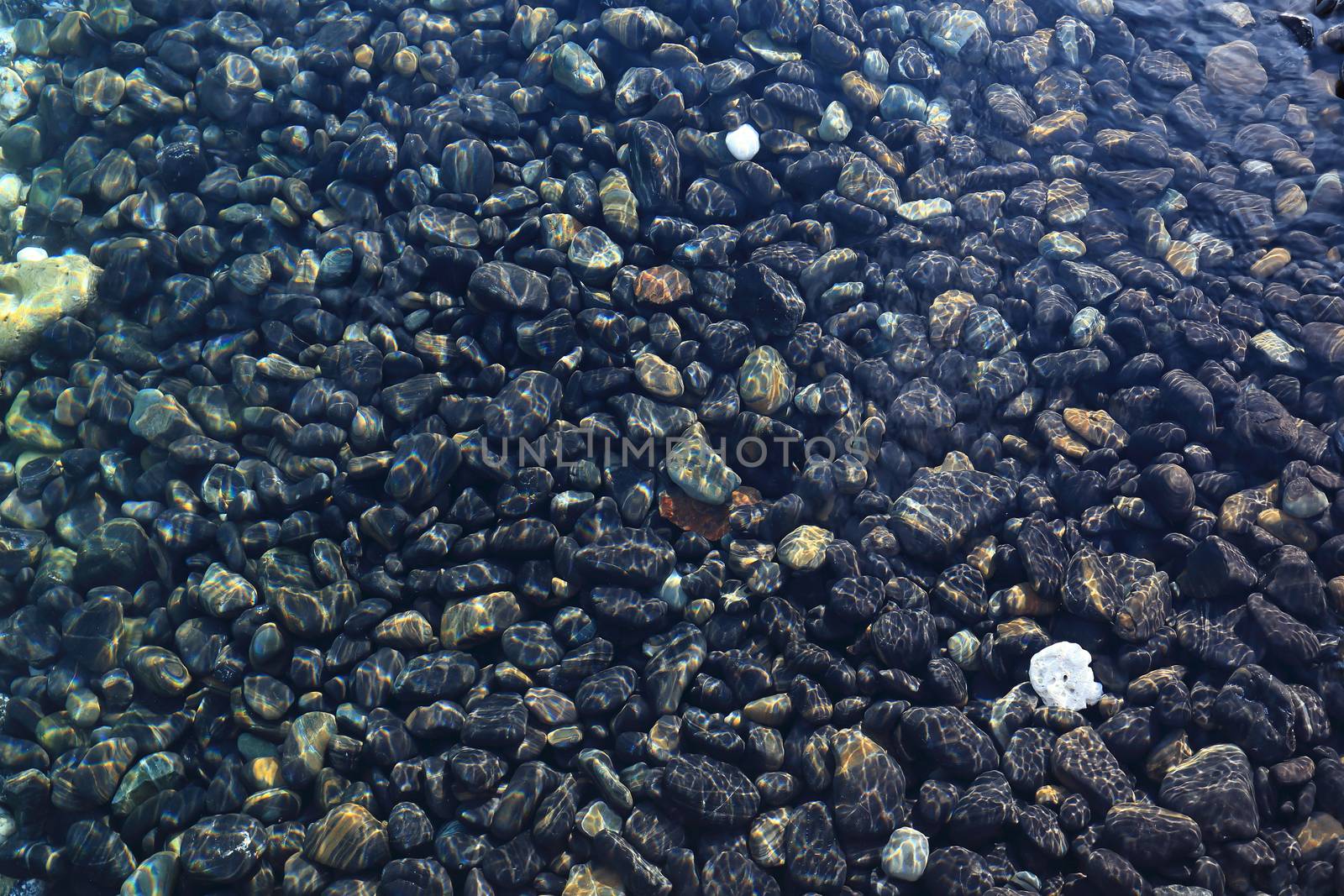 Colorful pebbles touching wave at beautiful rock island, called Koh Hin Ngam, near Lipe island, Thailand