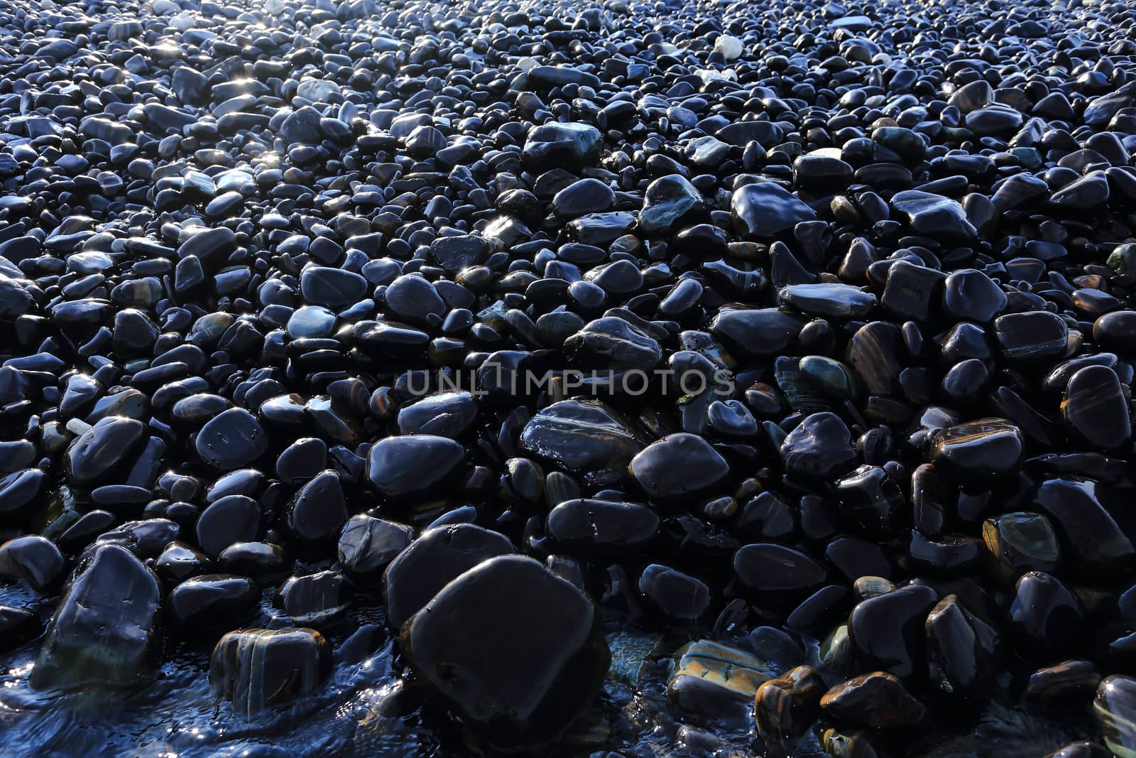 Colorful pebbles touching wave at beautiful rock island, called Koh Hin Ngam, near Lipe island, Thailand