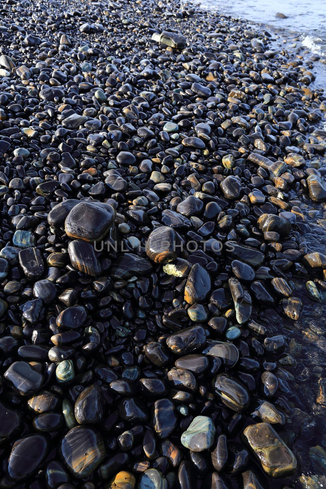 Colorful pebbles touching wave at beautiful rock island, called Koh Hin Ngam, near Lipe island, Thailand