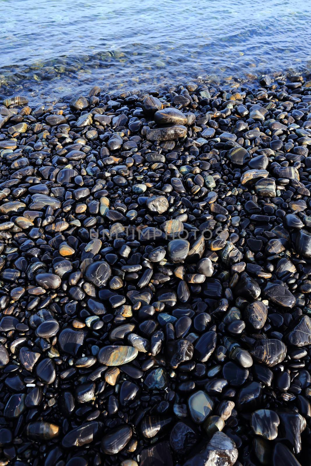 Colorful pebbles touching wave by rufous