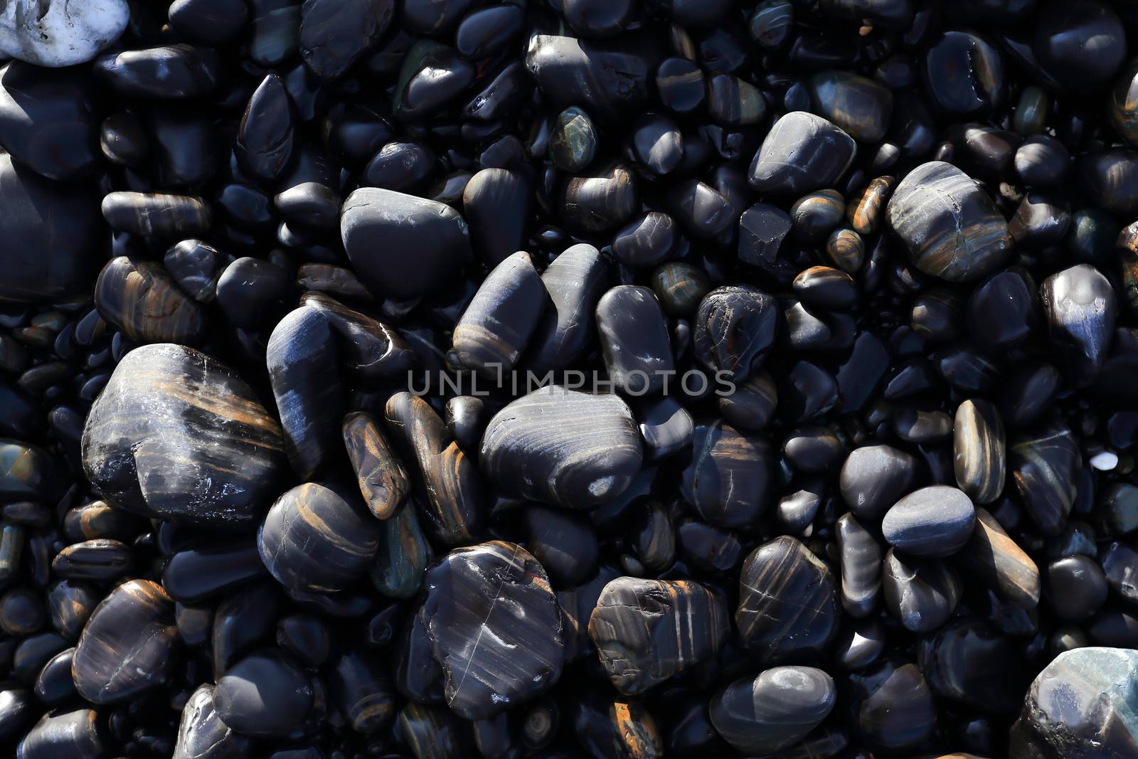 Colorful pebbles touching wave at beautiful rock island, called Koh Hin Ngam, near Lipe island, Thailand