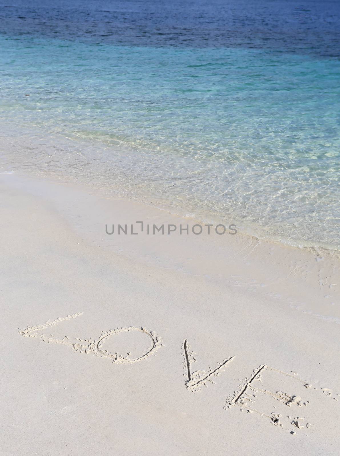Concept or conceptual hand made or handwritten Valentine`s day text in sand on a beach