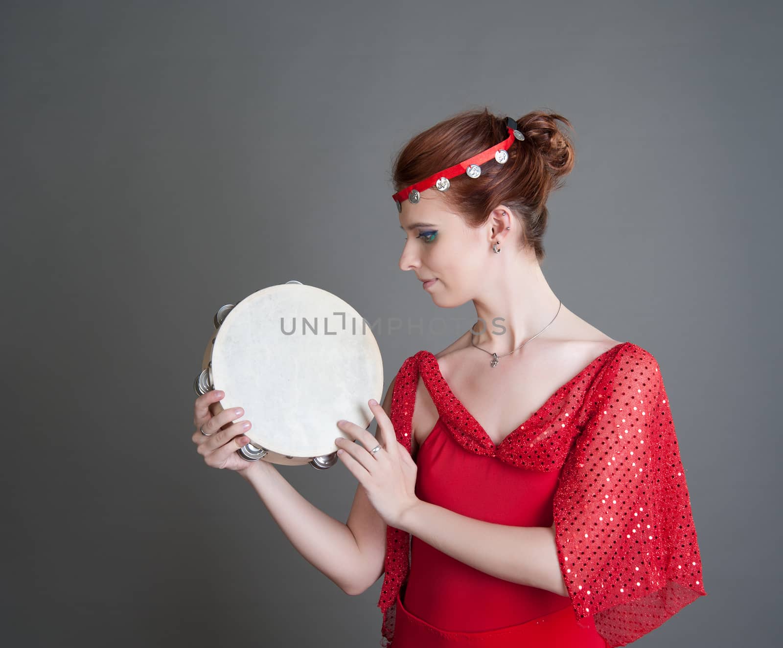 dancer in a red dress with a tambourine in Pointe on a grey background