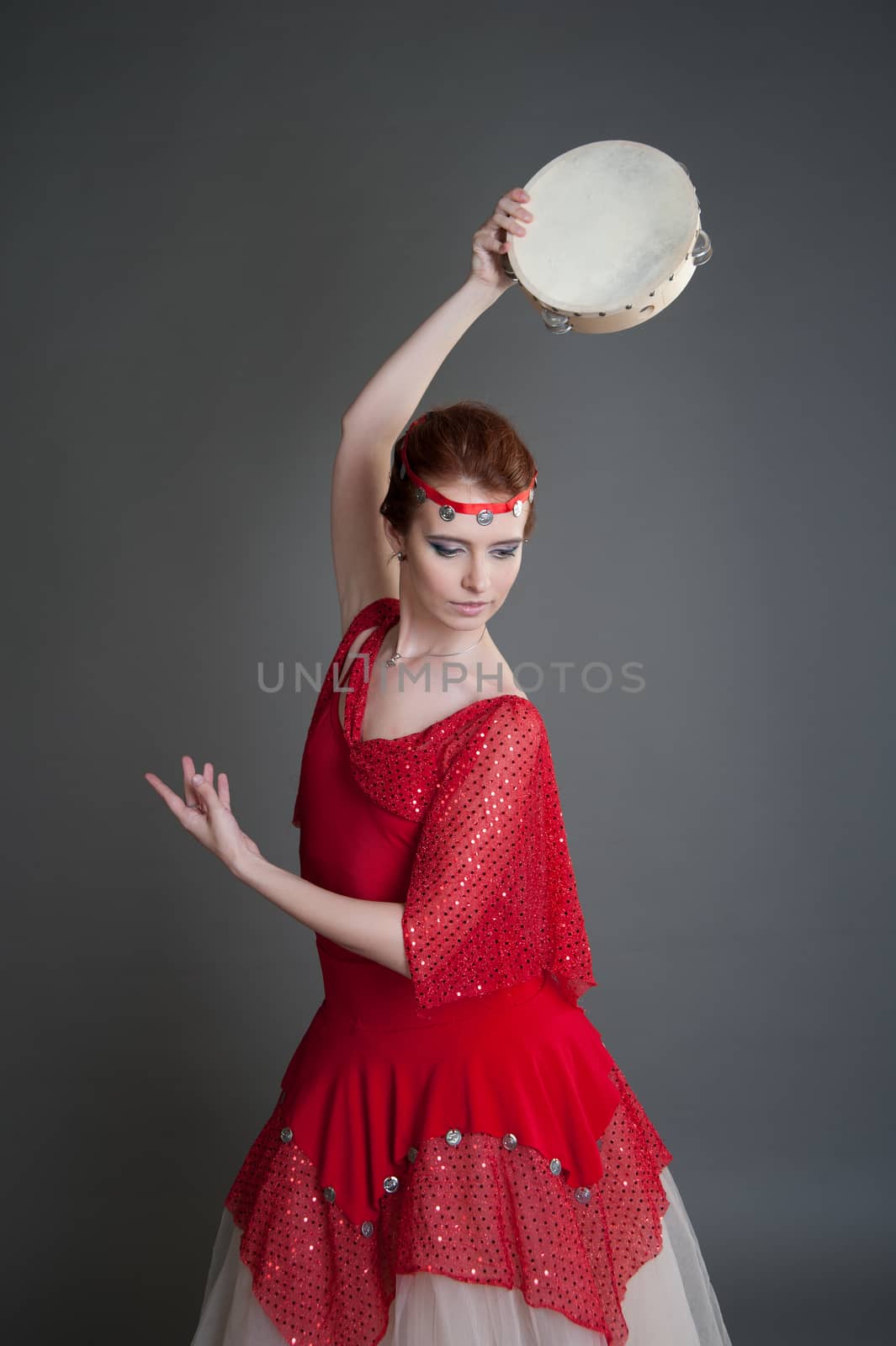 dancer in a red dress with a tambourine in Pointe on a grey background
