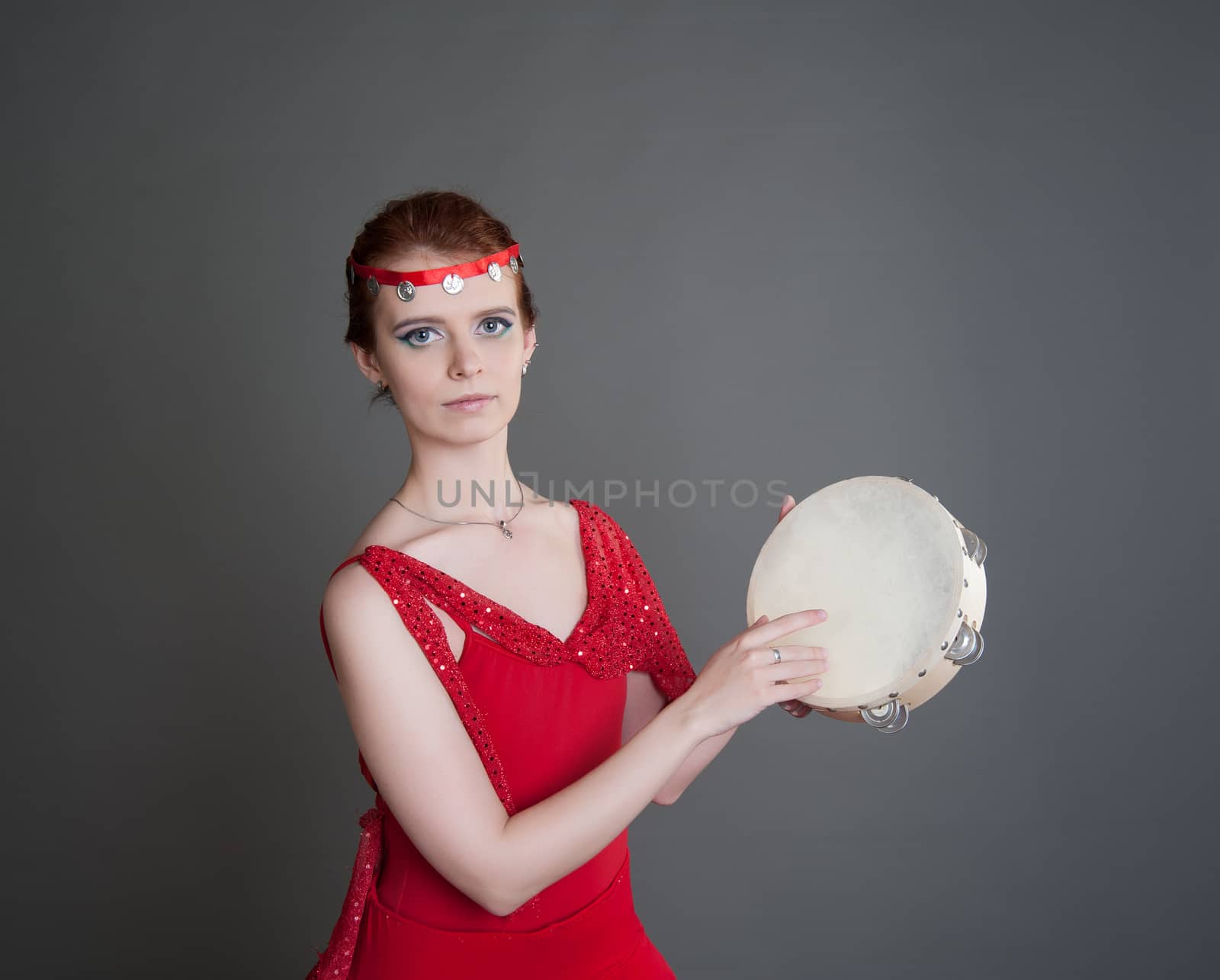 dancer in a red dress with a tambourine in Pointe on a grey background