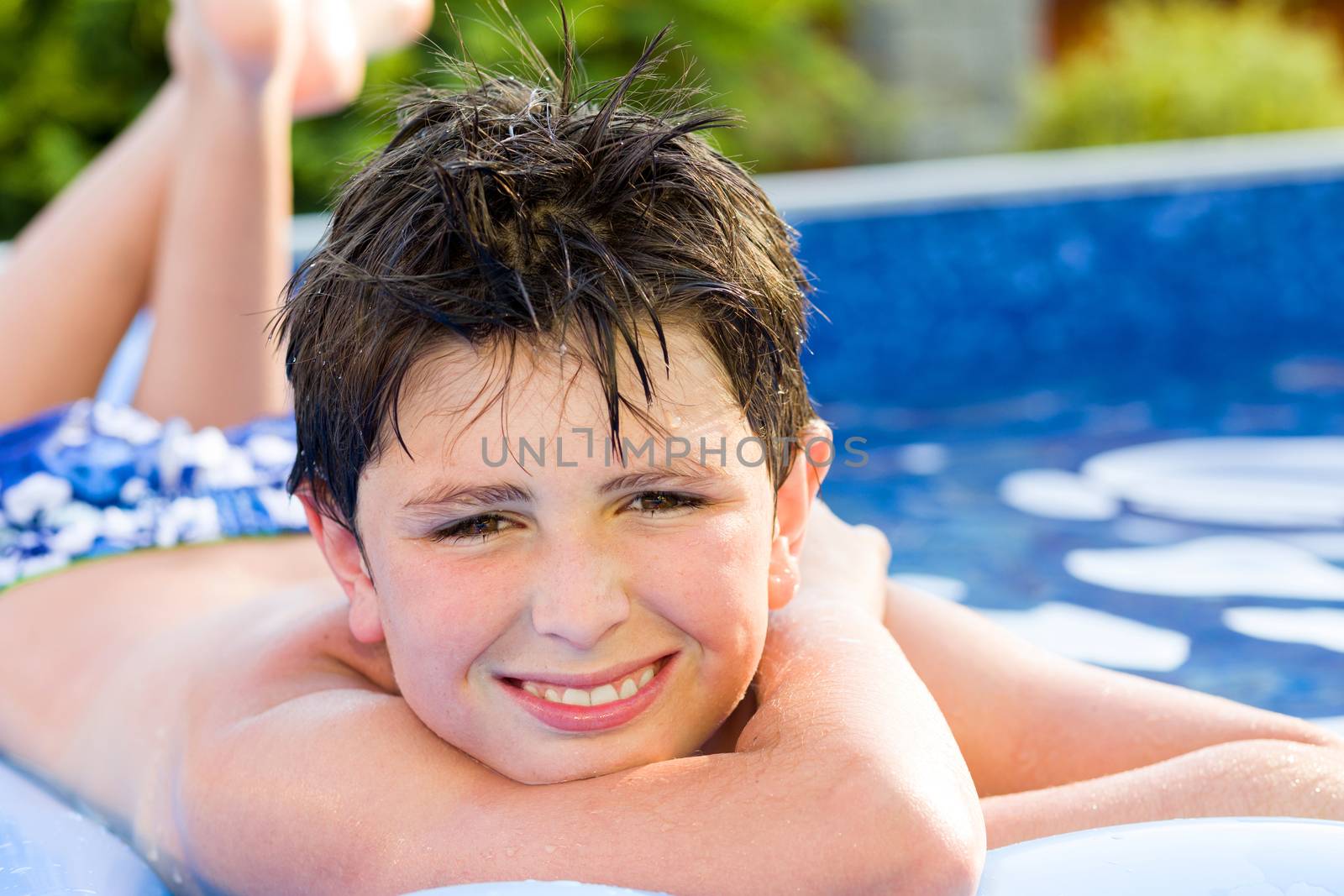 Happy young boy with inflatable water lounger in the swimming pool