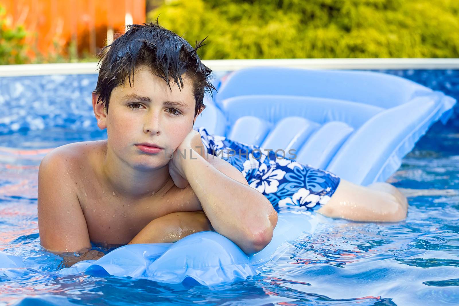 Happy young boy with inflatable water lounger in the swimming pool
