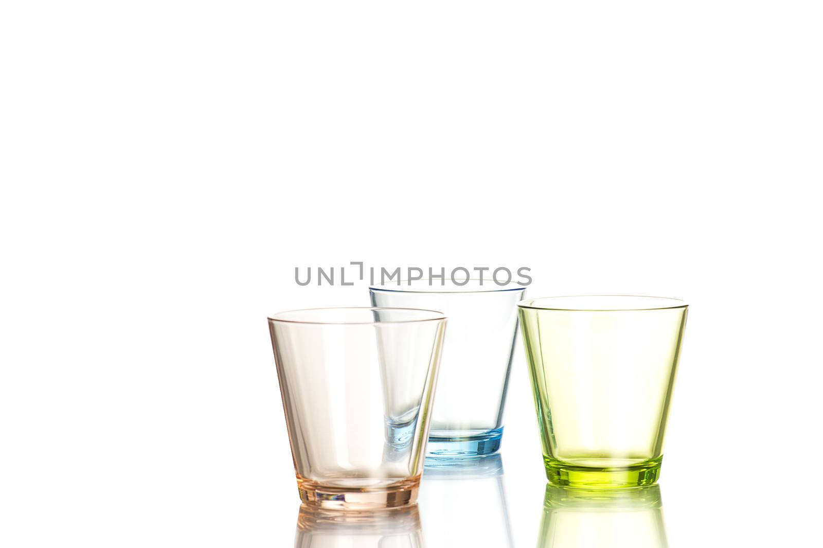 Three shot glasses colored brown, blue and green on white background