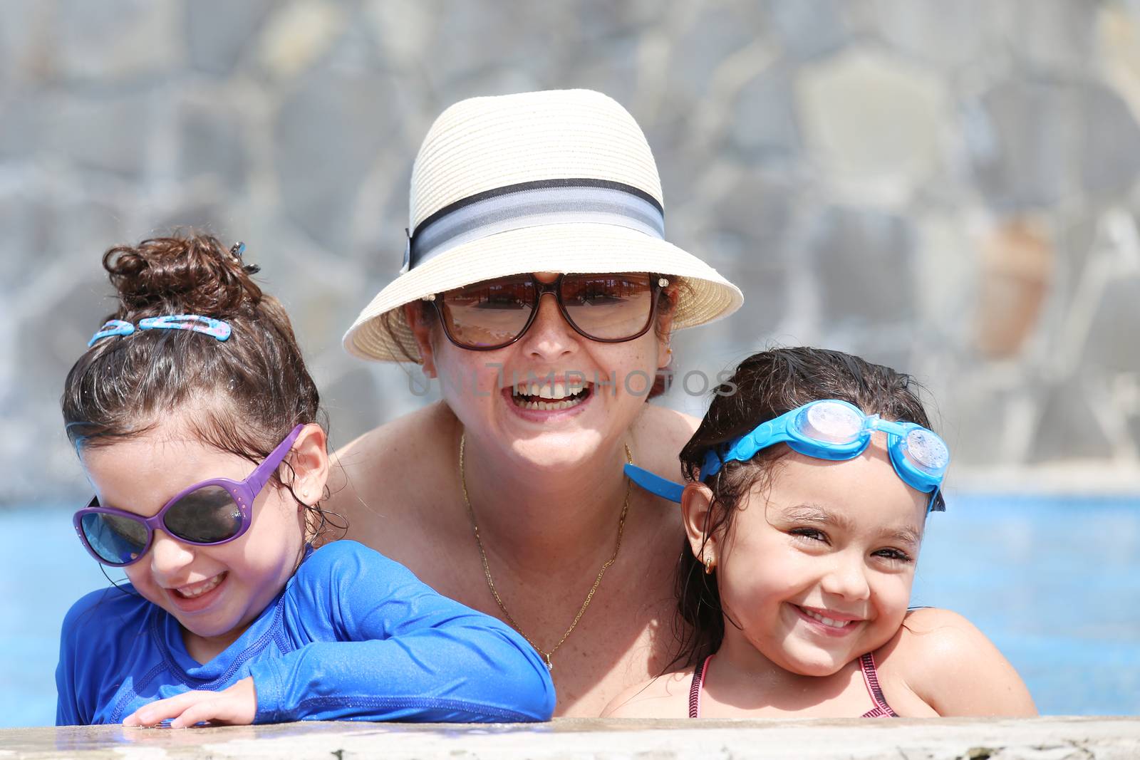 Happy mother with her kids in the pool by dacasdo