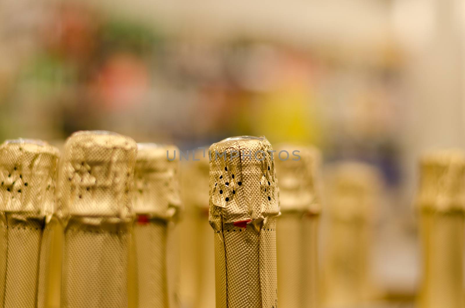 close up of champagne bottleneck cork wrapped yellow shiny paper