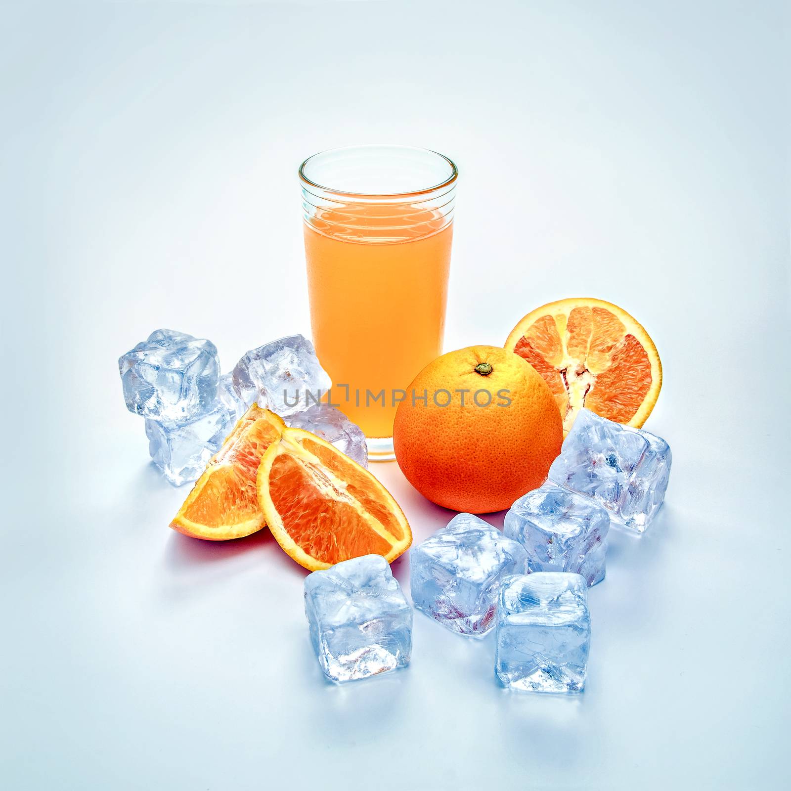 Glass of cool orange juice, ice and orange slices in he composition