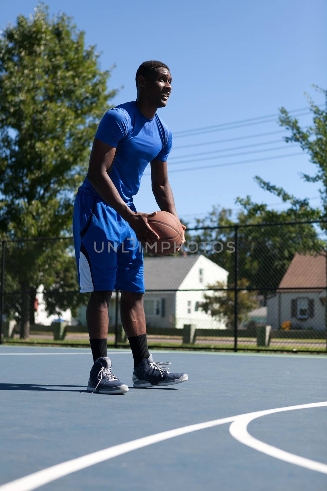 Basketball player shooting the ball at the basket on an outdoor court.