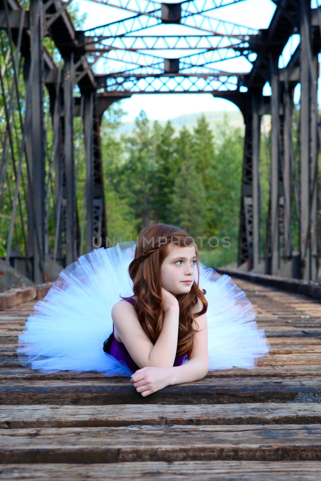 Beautiful girl wearing a white tutu lying on a bridge