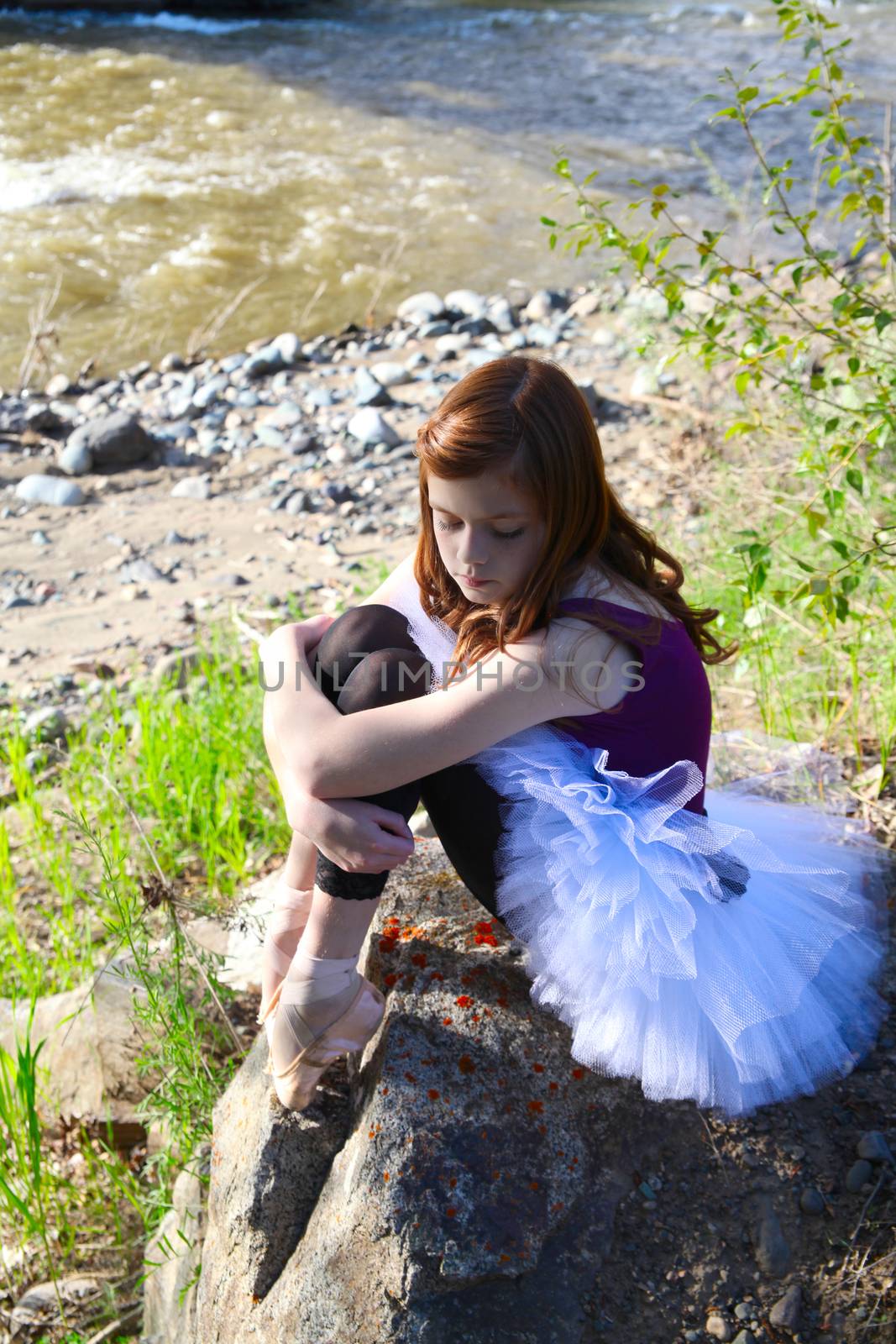 Beautiful girl wearing a white tutu sitting next to river