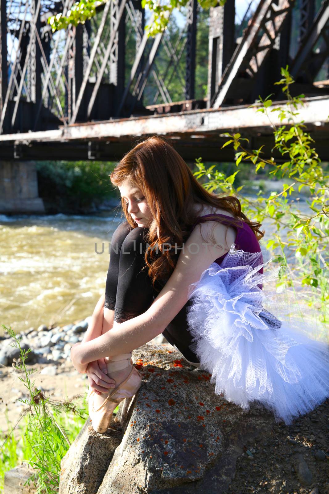 Beautiful girl wearing a white tutu sitting next to river