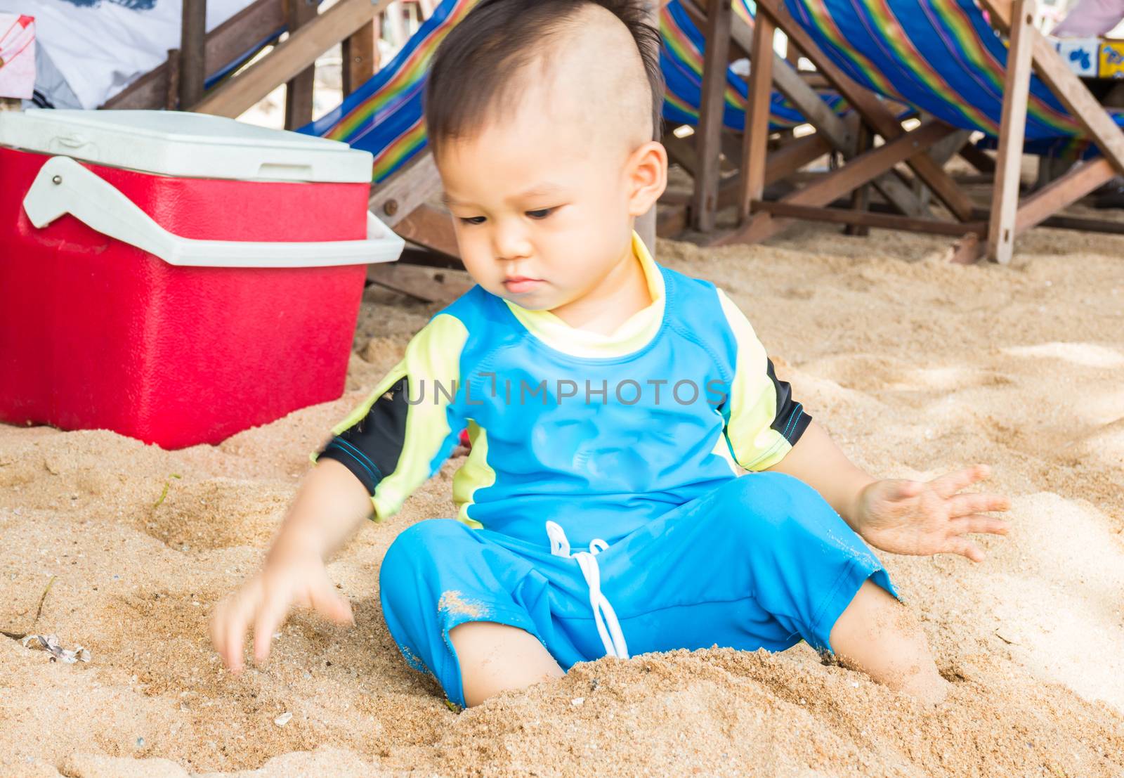 Little asian boy playing sand on the beach, stock photo