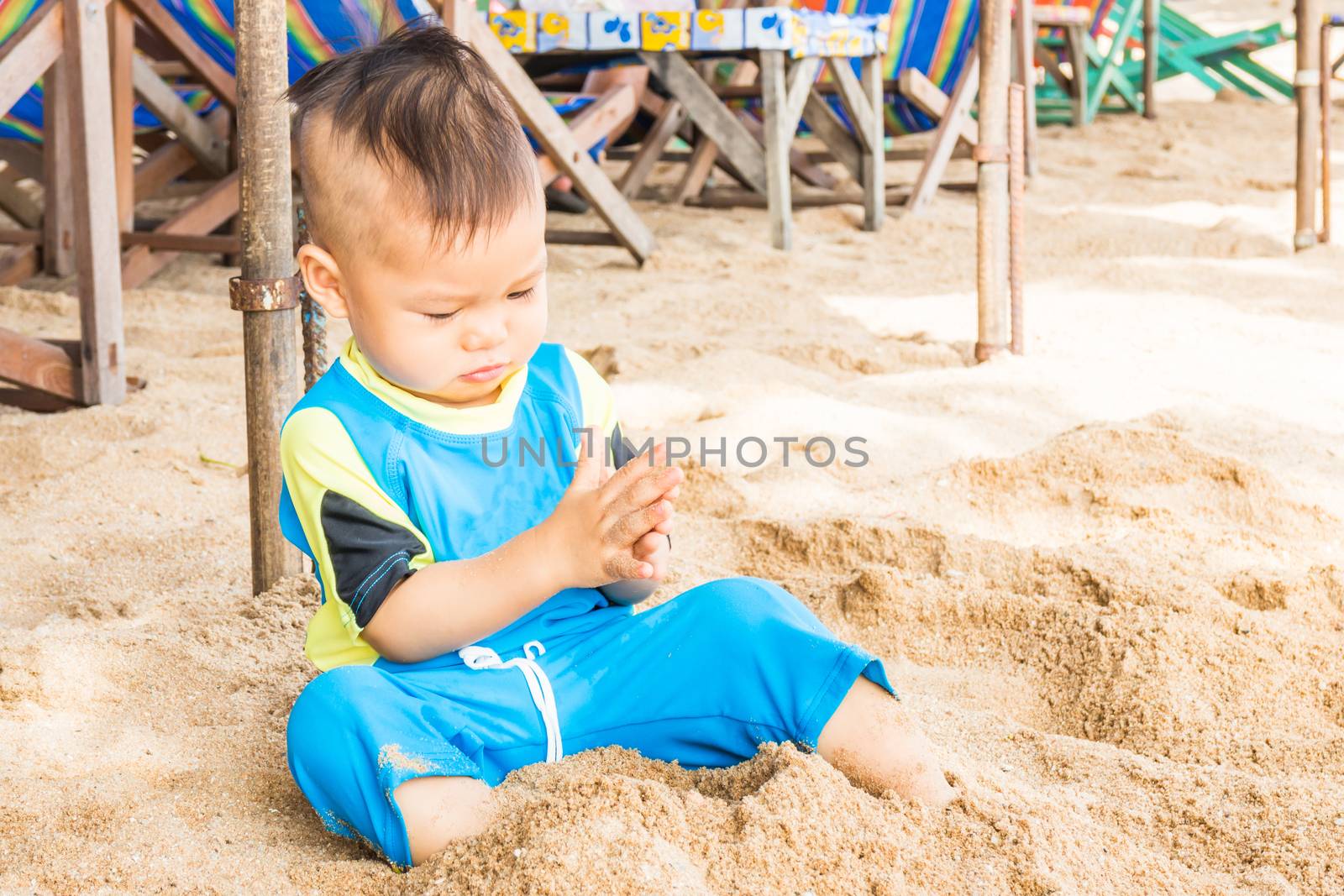 Asian cute boy playing sand on the beach, stock photo