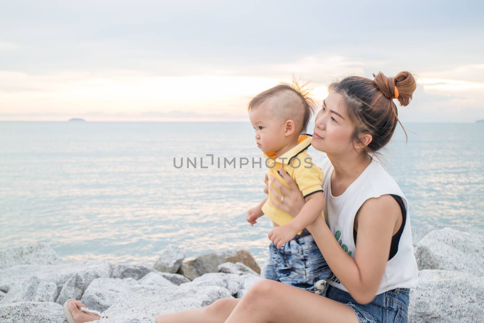 Asian boy chilling on the beach with his mother, stock photo