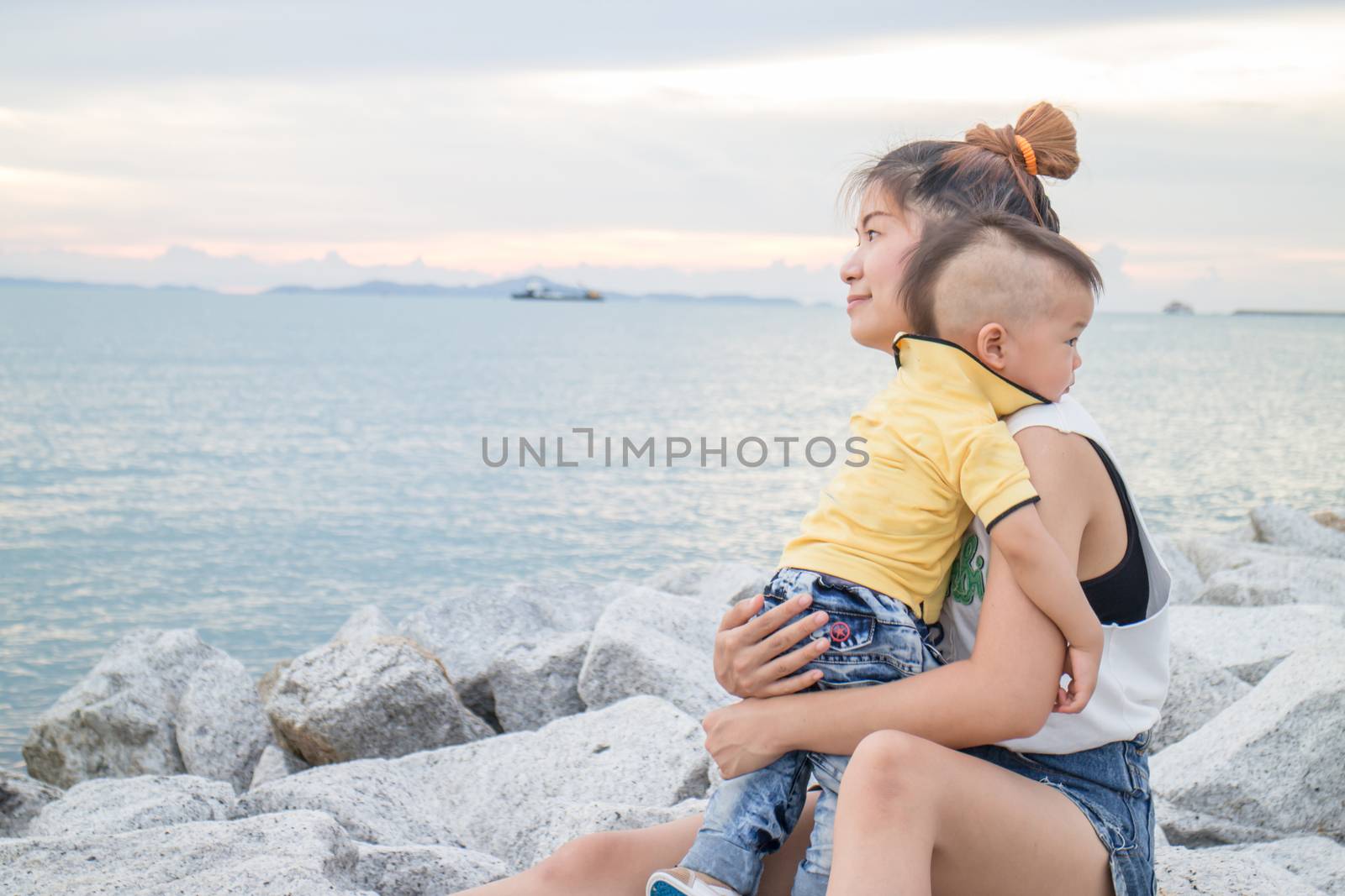 Asian boy chilling with his mother on seaside, stock photo