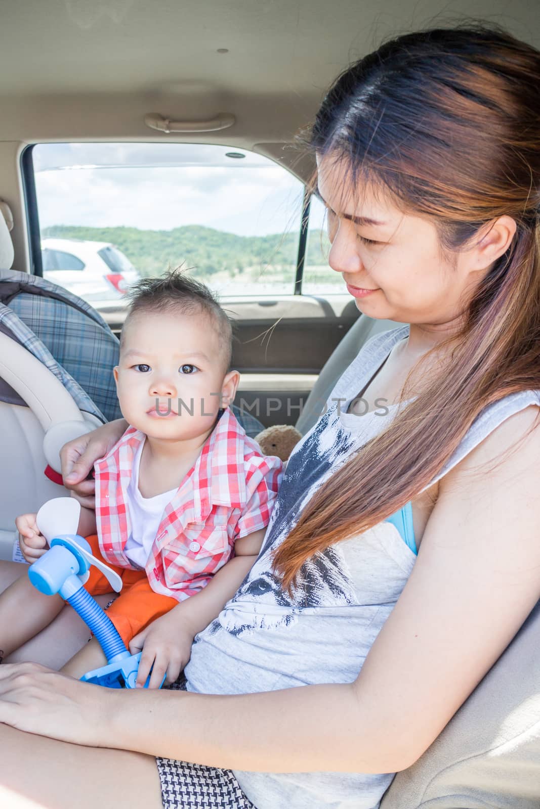 Cute boy sitting in the car with his mother, stock photo