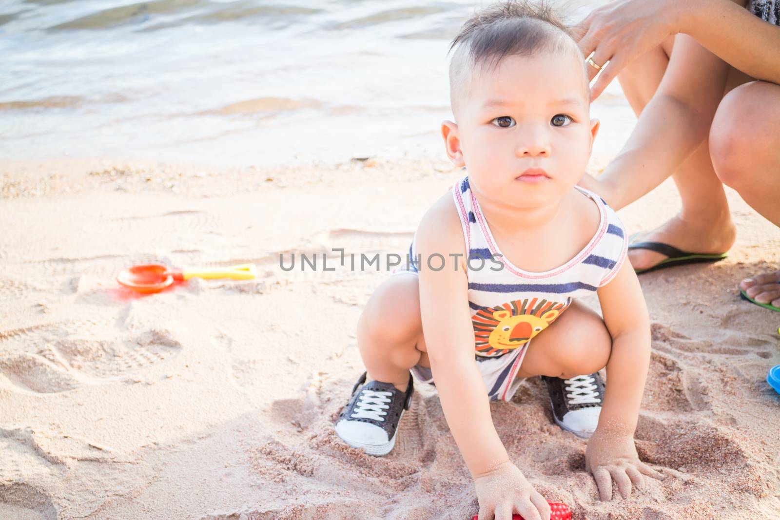 Little cute boy playing sand on the beach, stock photo