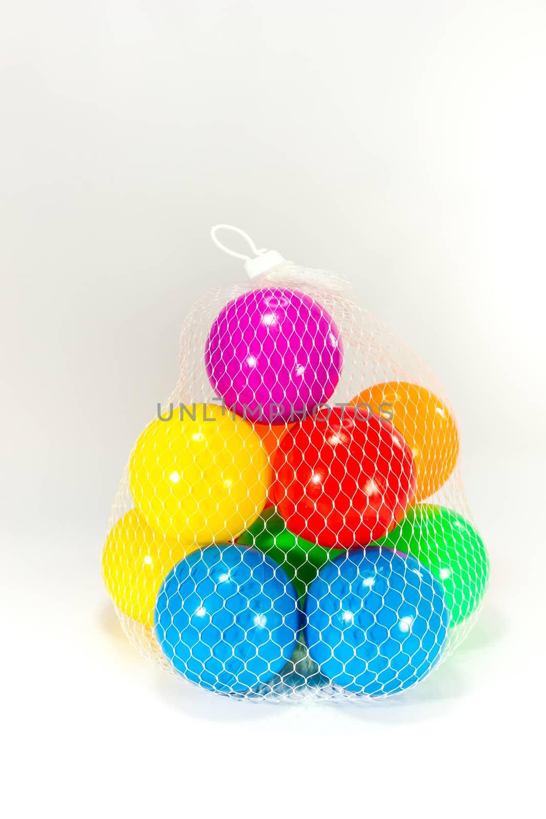 colorful plastic balls in net sac on white scene