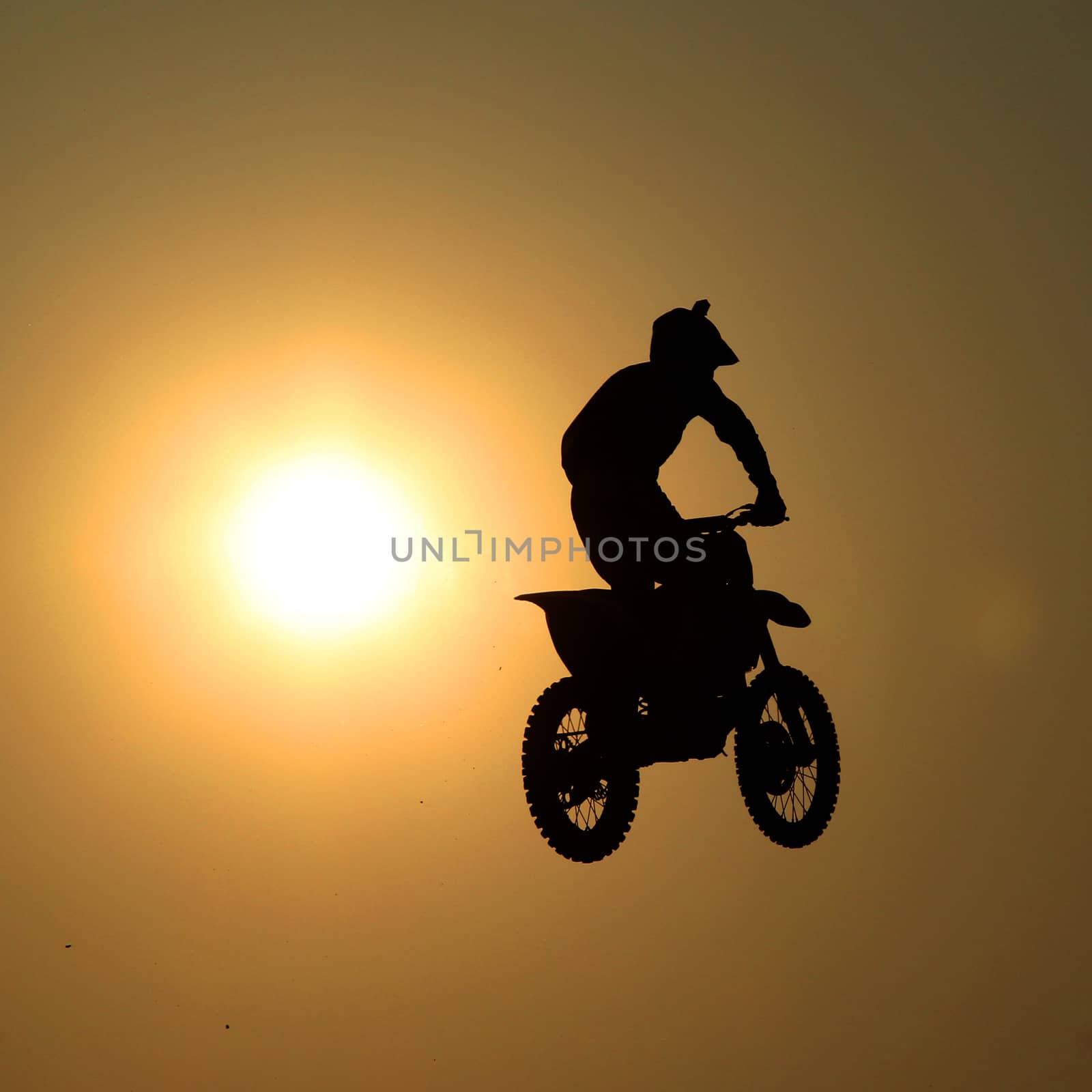 Motorcycle jumps in the air with sunset