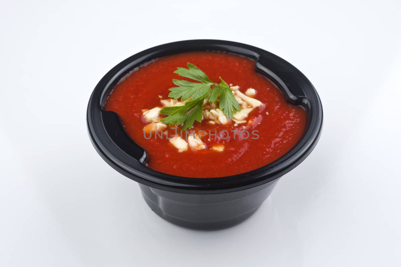 Tomato soup isolated on white with a basil garnish. Clipping path included.