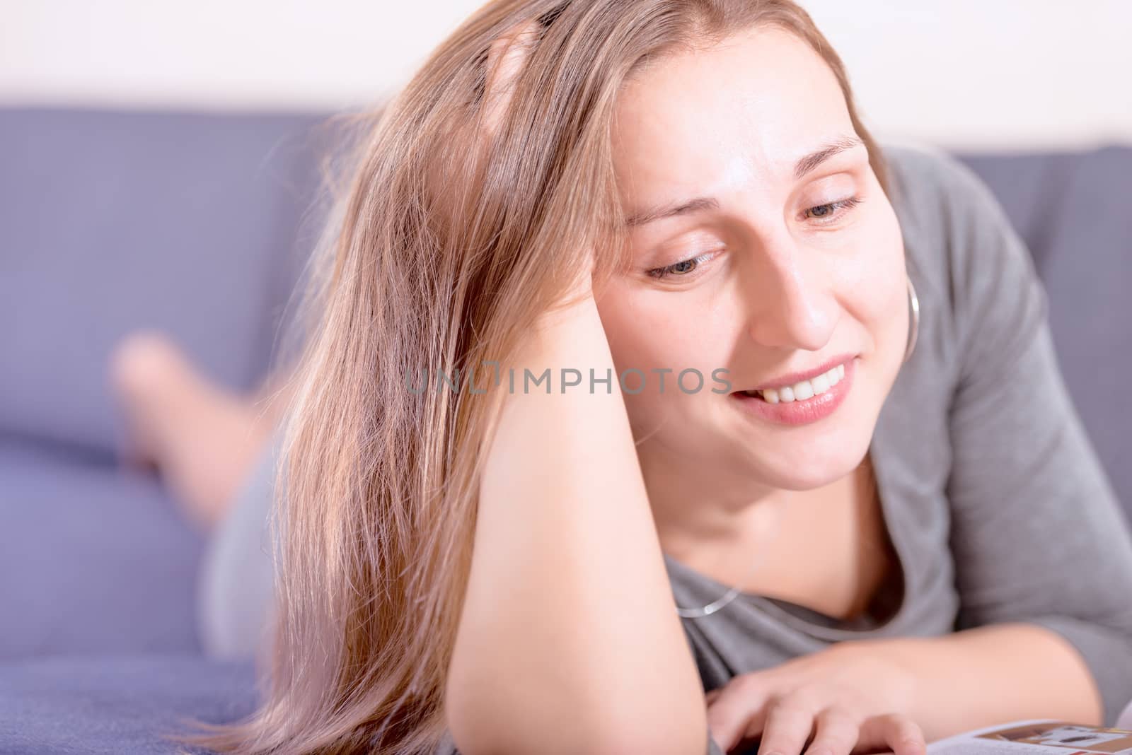 Brunette young woman reading on sofa