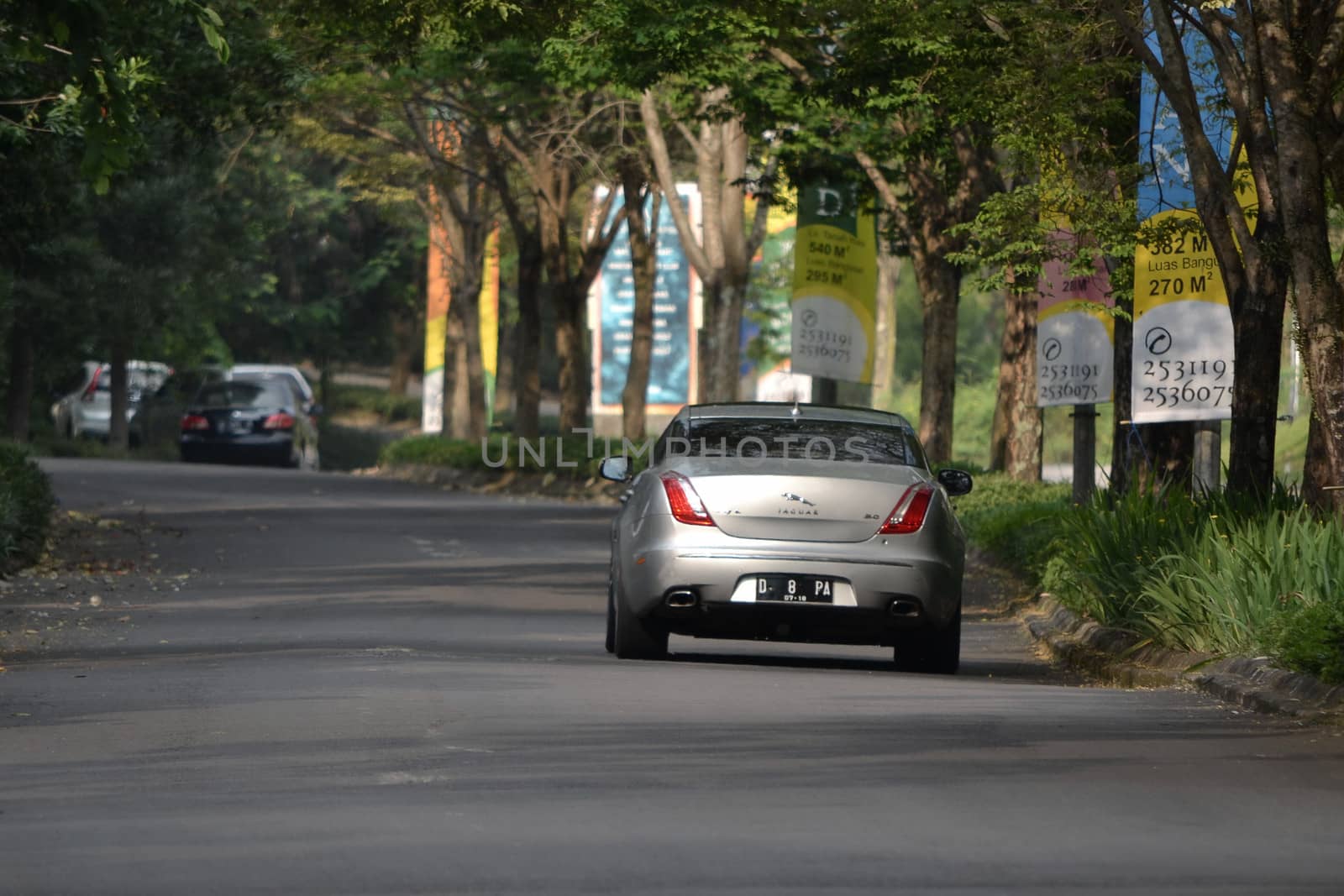 bandung, indonesia-june 9, 2014-grey colored jaguar car cruising on the road