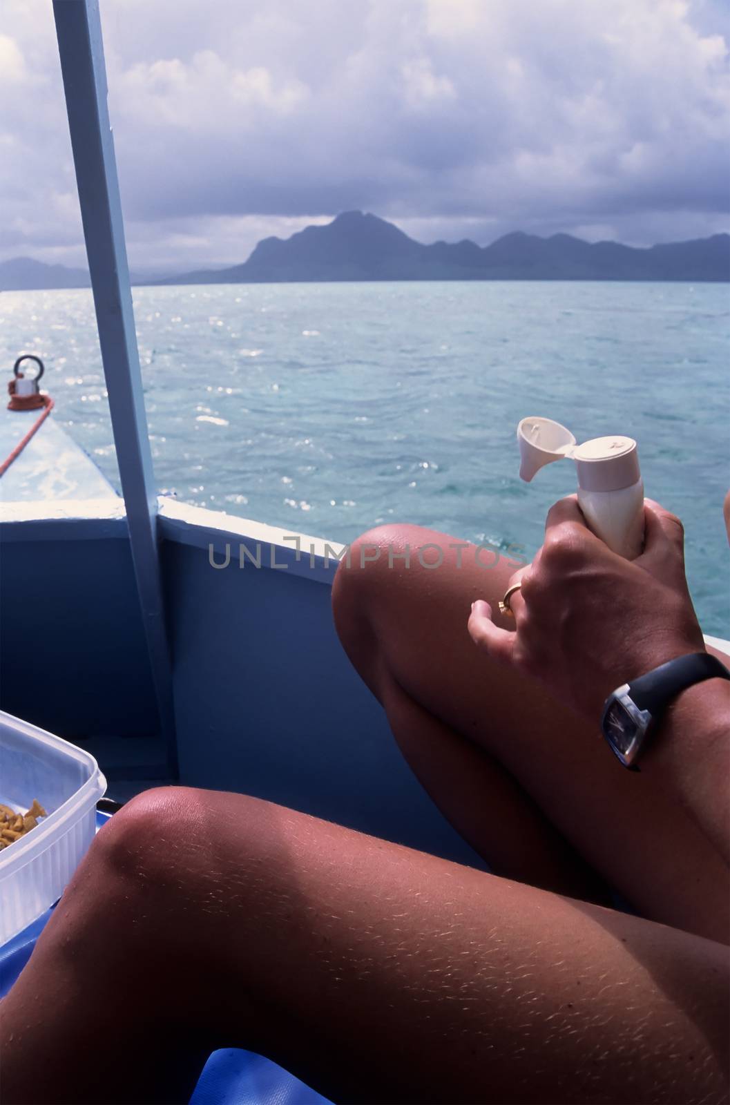 Sunbather on boat applying sun lotion, against an Indian Ocean i by seawaters