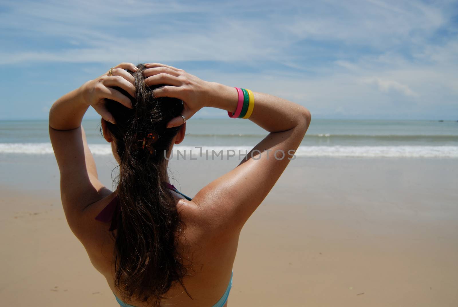 Stock photo of beautiful tall brunette woman on the beach in the by seawaters