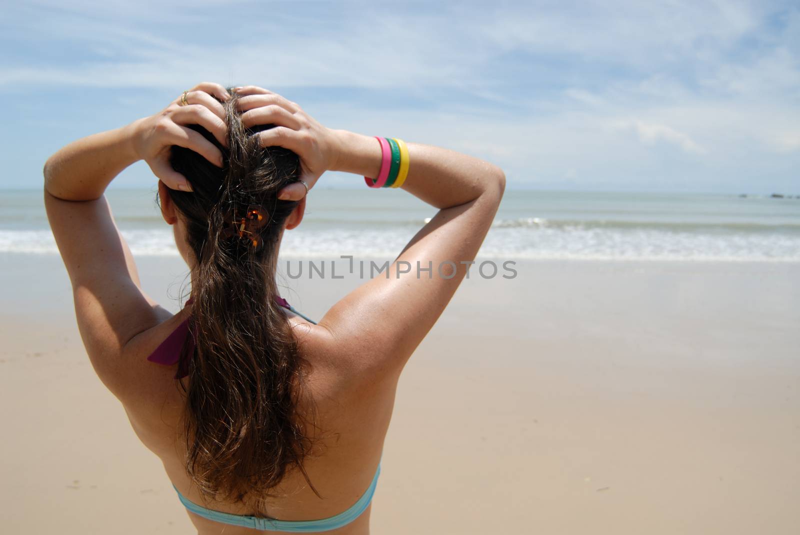 Stock photo of beautiful tall brunette woman on the beach in the by seawaters