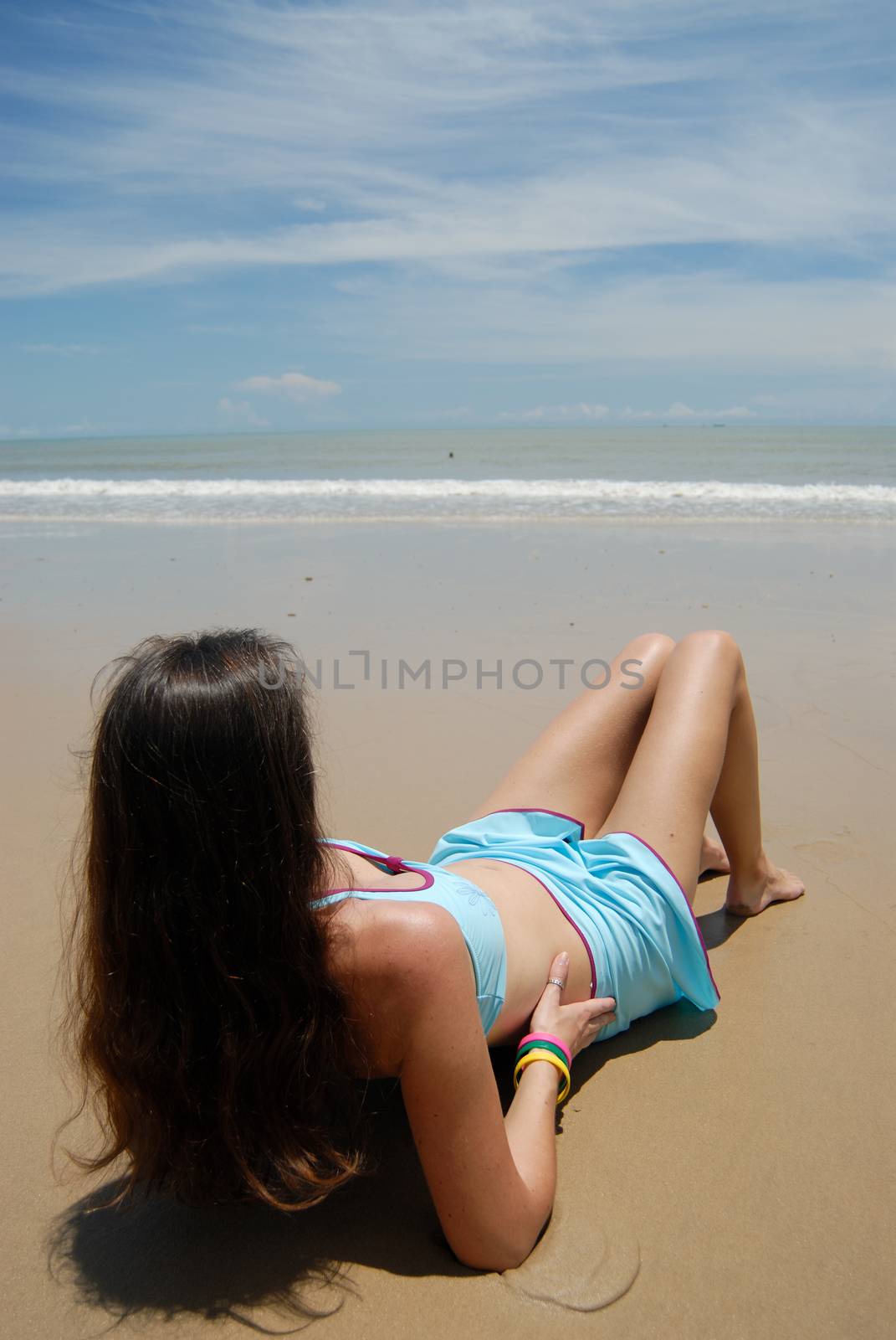 Stock photo of beautiful tall brunette woman on the beach in the by seawaters