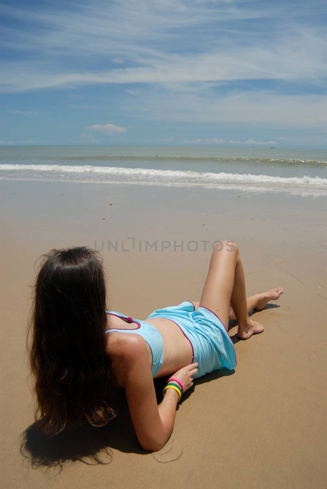 Stock photo of beautiful tall brunette woman on the beach in the by seawaters