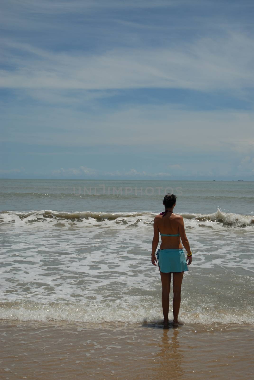 Stock photo of beautiful tall brunette woman on the beach in the by seawaters