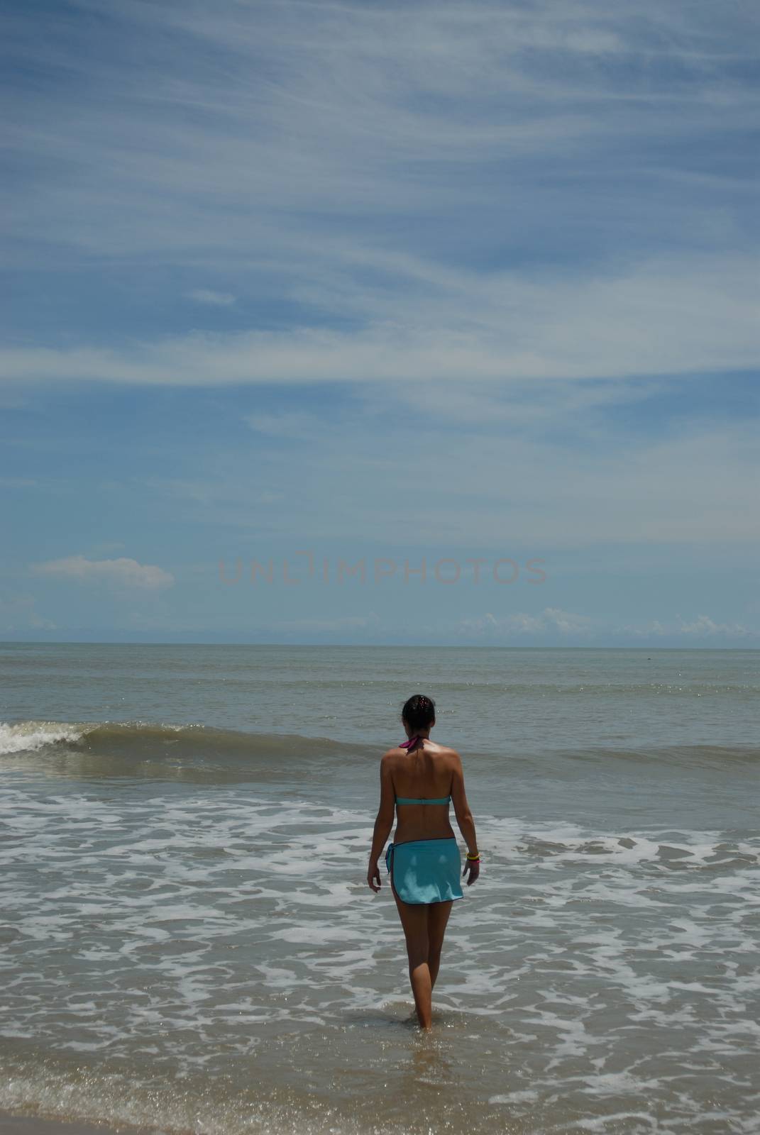 Stock photo of beautiful tall brunette woman on the beach in the by seawaters