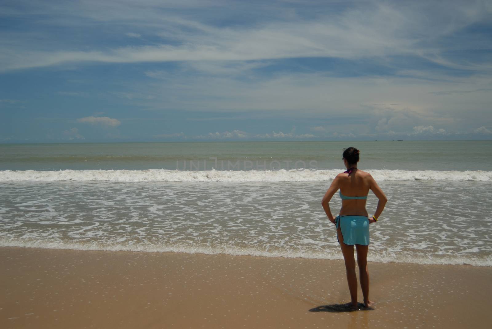 Stock photo of beautiful tall brunette woman on the beach in the by seawaters