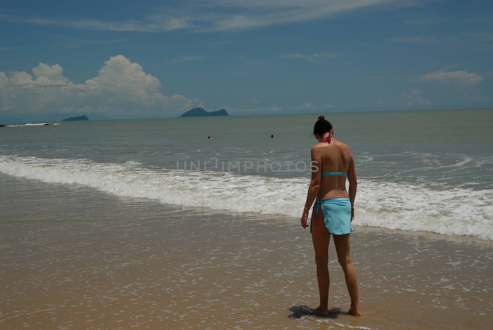 Stock photo of beautiful tall brunette woman on the beach in the tropics