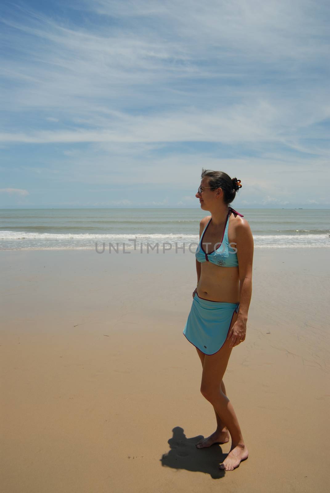 Stock photo of beautiful tall brunette woman on the beach in the by seawaters