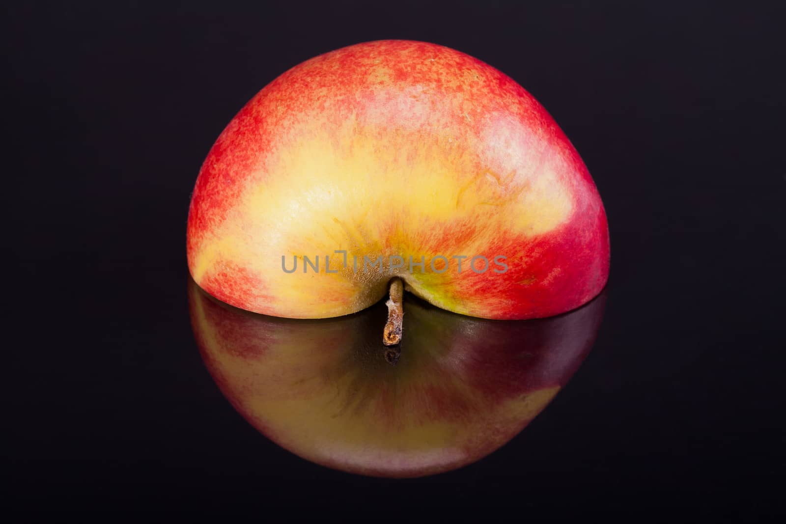half of red apple with reflection isolated on black background