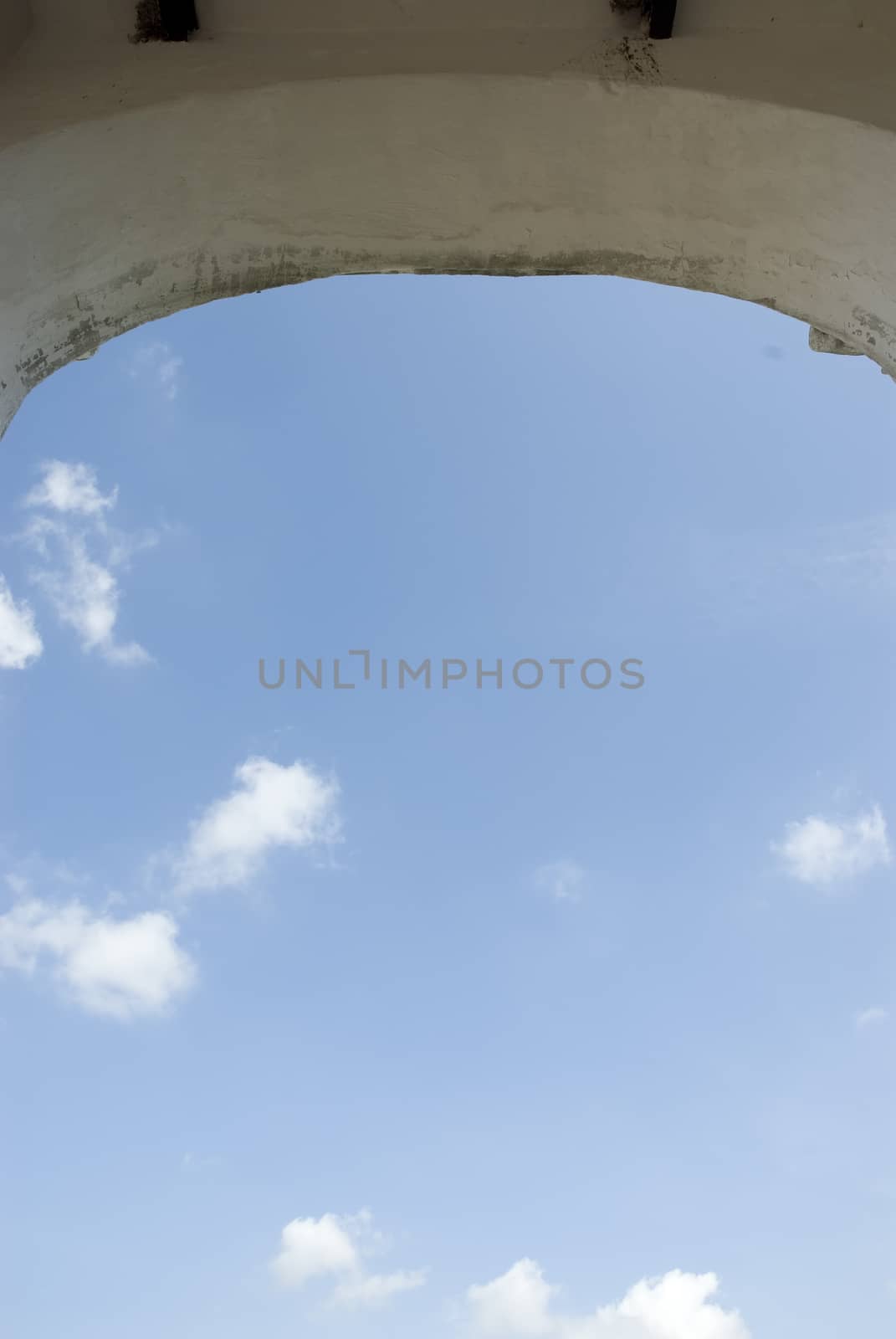 An arch of a building framing a blue summer sky