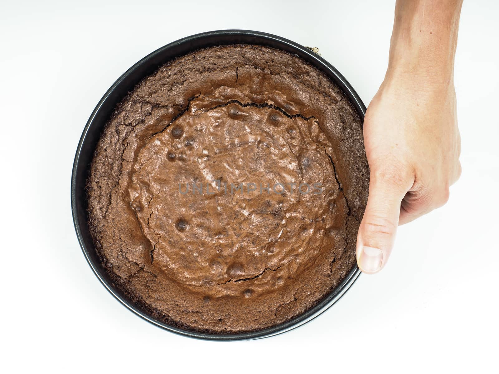 Freshly made chocolate cake in a round shape held by a person