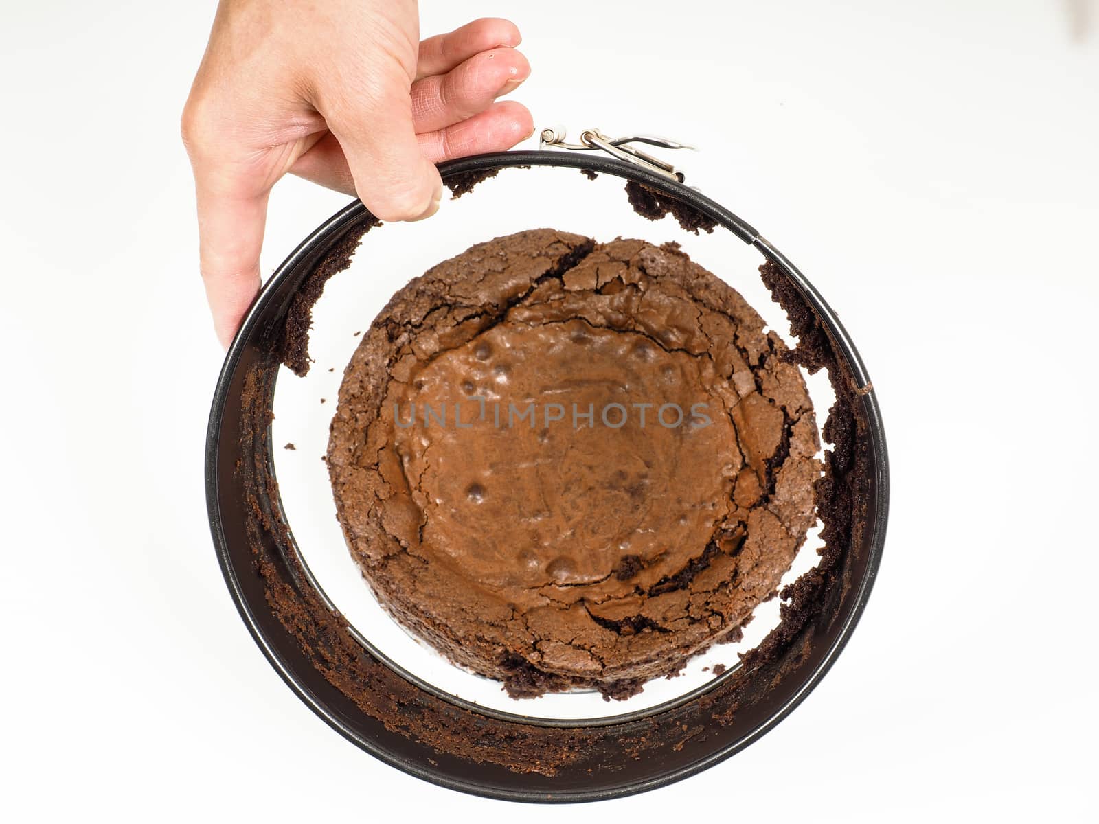 Person removing a round shape fomr fresh made chocolate cake