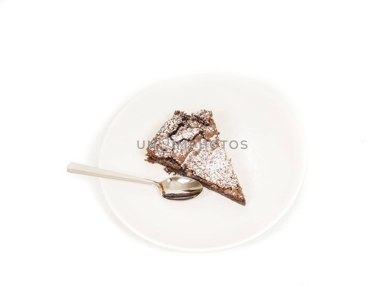 Piece of fresh made chocolate on plate with powdered sugar and teaspoon