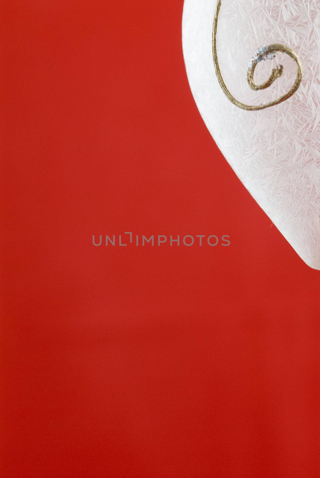 A white frosted glass Christmas decoration on red background