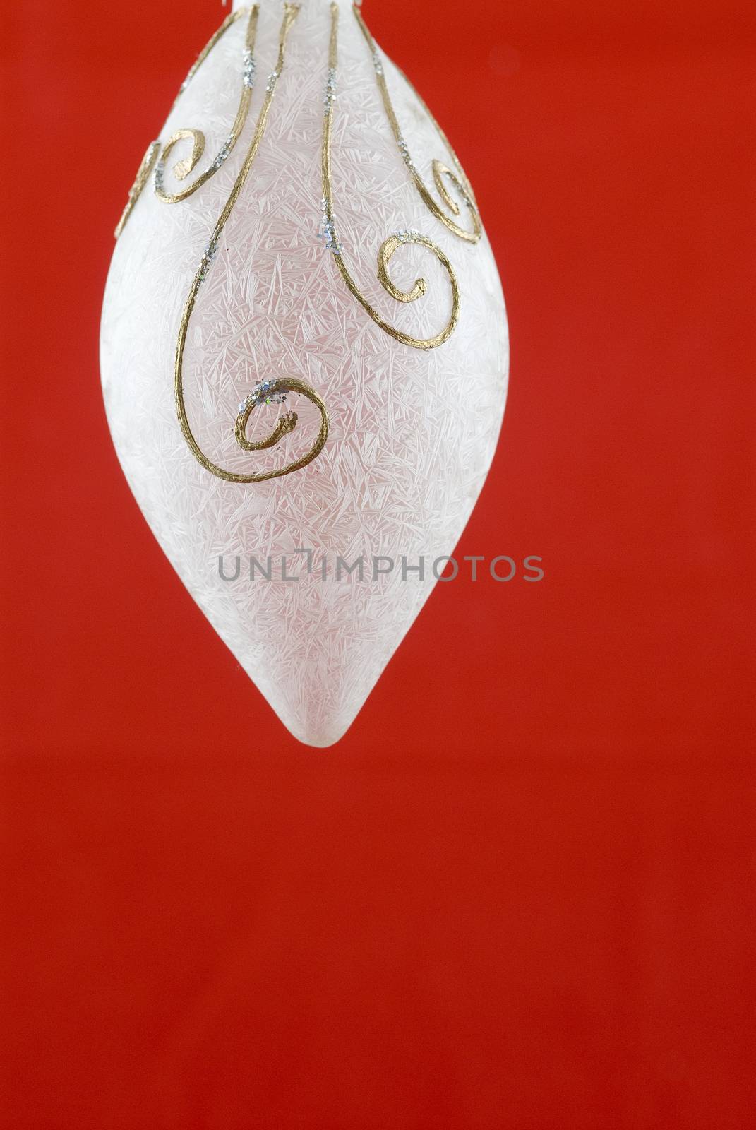 A white frosted glass Christmas decoration on red background